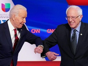 FILE: Democratic presidential hopefuls former US vice president Joe Biden (L) and Senator Bernie Sanders (R) greet each other with an elbow bump as they arrive for the 11th Democratic Party 2020 presidential debate in a CNN Washington Bureau studio in Washington, DC on Mar. 15, 2020.