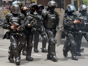 Police officers in riot gear secure the area where activists are holding protest against the prohibition of bearing a minimum dose of marijuana for consumption, in Bogota on September 6, 2018.