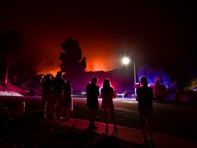 FILE: People watch as the Bobcat Fire burns on hillsides behind homes in Arcadia, California on Sept. 13, 2020 prompting mandatory evacuations for residents of several communities.