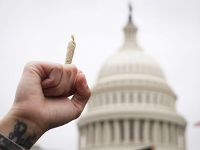 FILE: A pro-cannabis activist holds up a marijuana cigarette during a rally on Capitol Hill on April 24, 2017 in Washington, DC. /