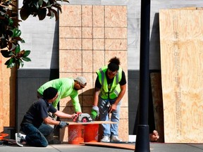 FILE: Workers cut panels of wood used for boarding up businesses, in expectation for election violence, a day before Election Day on Nov. 2, 2020 in Los Angeles, Calif. /