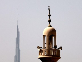 FILE: Burj Khalifa, the world's tallest tower, is silhouetted in the background of a mosque's minaret in Dubai in the United Arab Emirates, ahead of the Muslim fasting month, on Apr. 12, 2021. /