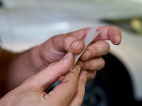 Close up of hands rolling a joint in front of a car. Concept of impaired driving