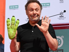 FILE: Comedian Billy Crystal holds up his hands after placing them in cement during his hand & footprint ceremony, Apr. 12, 2019 at the TCL Chinese Theatre in Hollywood, Calif. as part of the 2019 TCM Classic Film Festival. /
