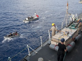 FILE - HMCS TORONTO prepares to hoist a raft of seized narcotics primed for explosive destruction.