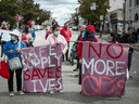 People hold banners at a march in Vancouver on International Overdose Awareness Day to remember those who died during the overdose crisis and to call for a safe supply of illicit drugs.