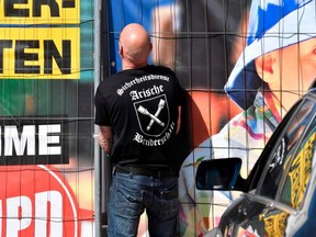 Image for representation: Private security personel with "Aryan Brotherhood" on his T-shirt opens the gate at the venue of the "Schild und Schwert" (Shield and Sword, or SS) neo-nazi festival, in the small eastern German town of Ostritz on Apr. 20, 2018. /