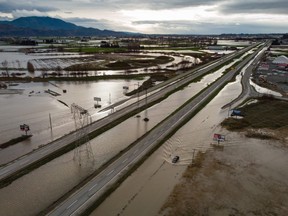 FILE: A motorist drives on a service road along the closed Trans-Canada Highway as floodwaters fill the ditches beside the highway and farmland in Abbotsford, B.C., on Wednesday, Dec. 1, 2021. /