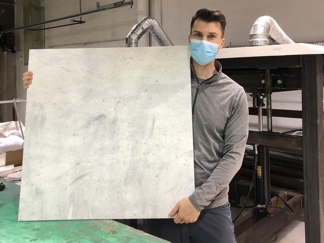 Corey Saban, founder and CEO of [RE] Waste, with a plastic sheet made  from diverted plastic waste. 