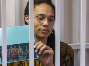 WNBA star and two-time Olympic gold medalist Brittney Griner holds up a photo of players from the recent all star game wearing her number, sitting in a cage at a court room prior to a hearing in the Khimki district court, just outside Moscow, Russia, Friday, July 15, 2022. Griner was arrested in February at the Russian capital's Sheremetyevo Airport when customs officials said they found vape canisters with cannabis oil in her luggage. She has been jailed since then, facing up to 10 years in prison if convicted.