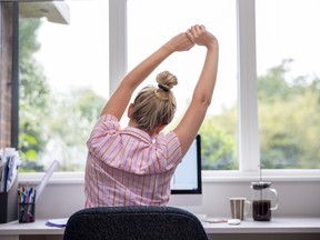 Woman in front of a laptop stretching