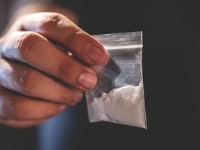 A man holds an unidentifiable bag of drugs