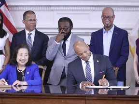 Maryland Gov. Wes Moore signs an executive order to issue more than 175,000 pardons for marijuana convictions on Monday, June 17, 2024 in Annapolis, Md. Maryland Secretary of State Susan Lee is seated left. Standing left to right are Lt. Gov. Aruna Miller, Maryland Attorney General Anthony Brown, Shiloh Jordan, Jason Ortiz, director of strategic initiatives for Last Prisoner Project and Heather Warnken, executive director of the University of Baltimore School of Law Center for Criminal Justice.