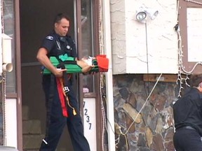A paramedic carries a baby injured in a fall from a window in Surrey on Sunday.