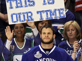 Kevin Bieksa looks on as a Vancouver Canucks fan holds a sign that reads, "BELIEVE THIS IS OUR TIME" prior to Game Seven against the Boston Bruins in the 2011 NHL Stanley Cup Final at Rogers Arena on June 15, 2011 in Vancouver, British Columbia, Canada.  (Photo by Elsa/Getty Images)