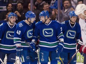 Chris Higgins (second from right) celebrates with Maxim Lapierre with Dan Hamhuis (left) and Kevin Bieksa in the background during a 7-4 win over Washington Saturday night at Rogers Arena. (Rich Lam/Getty Images) [PNG Merlin Archive]