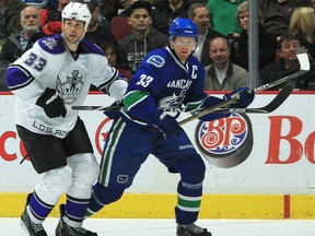 Henrik Sedin tries to get past Willie Mitchell's big stick, the league-maximum 63 inches long.