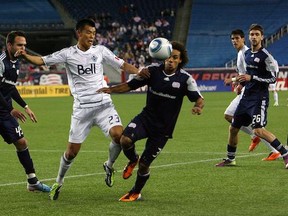 Caps' forward Long Tan takes on a pair of New England Revs. (Gail Oskin/Getty Images)