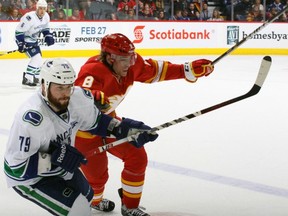 Mike Duco and former Abbotsford Heat forward Kris Kolanos fight for a loose puck on Saturday at Calgary.