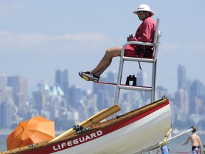 Lifeguards such as this fellow keeping an eye on swimmers at Spanish Banks in July may be a rarer sight thanks to proposed parks board cuts. (Les Bazso/PNG FILES)