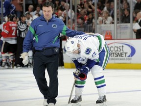 Canucks medical trainer Mike Burnstein helps Daniel Sedin off the ice in Chicago last week after Duncan Keith's vicious albow to the head.