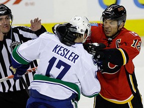 Canucks' Ryan Kesler (C) and Calgary Flames' Jarome Iginla mix it up during second period action as Linesmen Shane Heyer (L) tries to break them up in their NHL hockey game in Calgary.