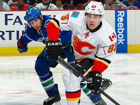 Mike Cammalleri #93 of the Calgary Flames makes a pass while being checked by Ryan Kesler #17 of the Vancouver Canucks during their NHL game at Rogers Arena March 31, 2012 in Vancouver, British Columbia, Canada.  Vancouver won 3-2. (Photo by Jeff Vinnick/NHLI via Getty Images)