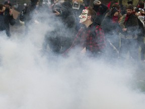 Masked protesters are enveloped in tear gas during violent demonstration outside the convention of the Quebec Liberal Party in Victoriaville east of Montreal on Friday May 4. (POSTMEDIA NEWS FILES)