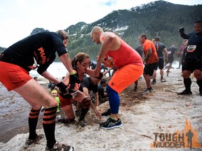 Two Tough Mudder participants lend a helping hand to a third 'mudder' following an ice-cold swim during Saturday's Tough Mudder event in Whistler, B.C. (FROM FACEBOOK)