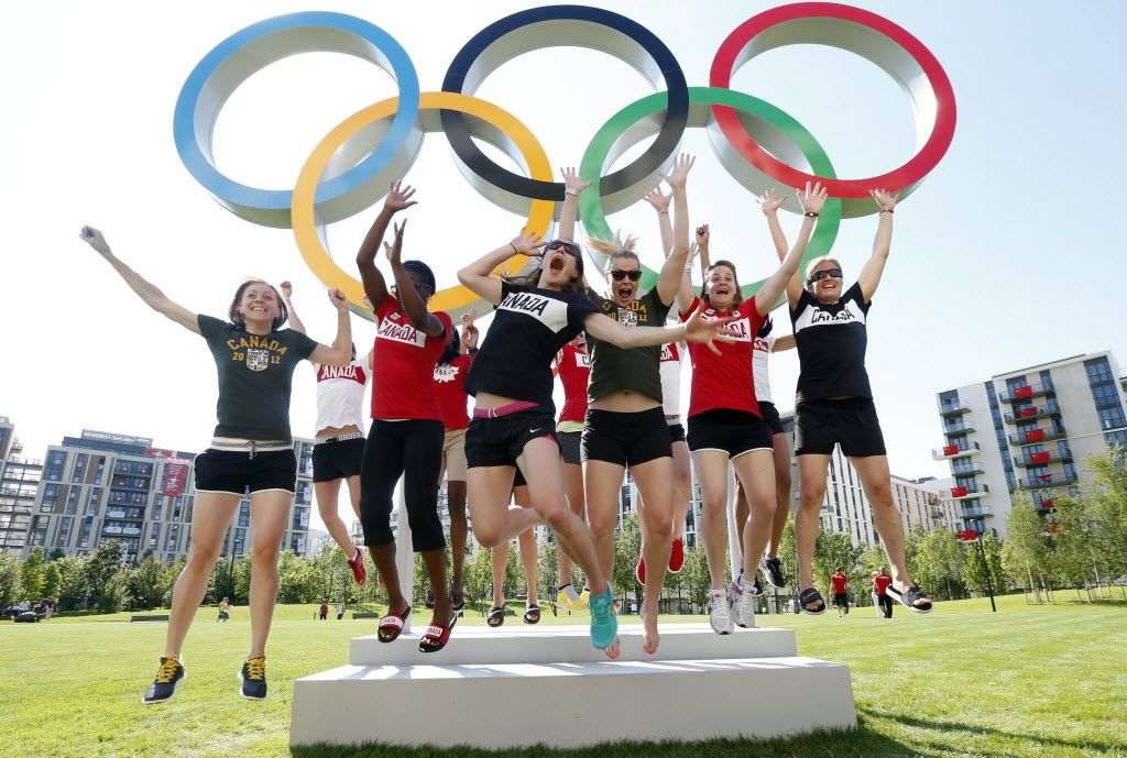 Members of Canada's Olympic basketball team jump for joy in front of the rings at London's Olympic Village on Tuesday. AP photo.