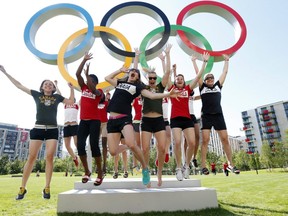 Members of Canada's Olympic basketball team jump for joy in front of the rings at London's Olympic Village on Tuesday. AP photo.