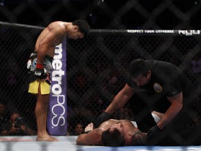 Lyoto "The Dragon" Machida bows as referee John McCarthy tends to Ryan Bader. (photo courtesy of Esther Lin/MMA Fighting UFC on FOX 4 Gallery)