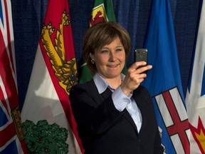 Premier Christy Clark uses her smart phone to take a photograph of the assembled media as she fields questions as the premiers gather for an economic summit in Halifax on Friday, Nov. 23 (THE CANADIAN PRESS)