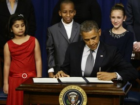 Hinna Zeejah, 8, Taejah Goode, 10, and Julia Stokes, 11, who wrote letters to U.S. President Barack Obama about the Newtown, Conn., school shooting watch as he signs executive orders outlining proposals to reduce gun violence. — AP Photo