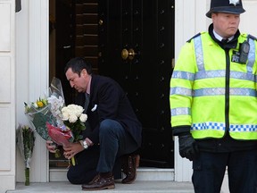 A member of the household collects floral tributes from the front doorstep at the home of former British Prime Minister Margaret Thatcher in central London on Wednesday. (Leon Neal/AFP/Getty Images)