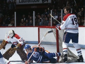Larry Robinson of the Montreal Canadiens stands over the Edmonton Oilers star Wayne Gretzky, with Habs goalie Richard Sevigny focused on the puck. Getty Images file photo.
