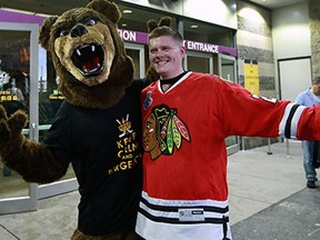 BOSTON - JUNE 17: A fan dressed as a Bruins bear greets other fans outside of the Garden, and as he posed for a photo being shot by the other fan's friend, he gave the rabbit ears to Blackhawks fan T.J. Budka of Ayer, Mass., originally from Illinois. The Boston Bruins hosted the Chicago Blackhawks for Game Three of the Stanley Cup Finals at the TD Garden, June 17, 2013. (Photo by Jim Davis/The Boston Globe via Getty Images)