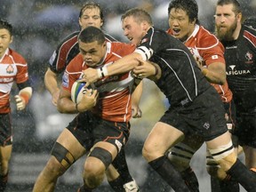 Japan's Hendrik Tui, left, is tackled by Canadian flanker Aaron Flagg during their Pacific Nations Cup rugby tournament match in Nagoya, central Japan, Wednesday, June 19, 2013. Japan rallied to beat Canada 16-13. (AP Photo/Kyodo News)