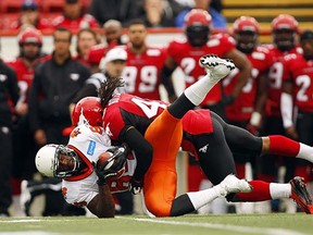 Lions receiver Emmanuel Arceneaux, left, grimaces as he is tackled by Calgary Stampeders' Troy Butler during preseason action June 14 in Calgary. (Jeff McIntosh/CP)