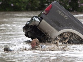 Kevan Yaets swims after his cat Momo to safety as the flood waters sweep him downstream and submerge the cab in High River, Alberta.PHOTO BY JORDAN VERLAGE