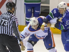 The Canucks' Kyle Hope and the Oilers' Gregory Chase fight in Penticton on Sept. 8, 2013. Ward Perrin -- PNG photo.