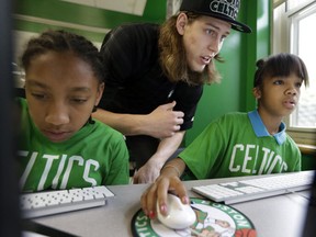 Boston Celtics basketball draft pick Kelly Olynyk assists Jillian Ayler, 11, (left) and Kanashia Howard, 12, both of Boston, in a technology lab at the Mildred Ave Teen Center in Boston on July 1. (AP Photo/Steven Senne)