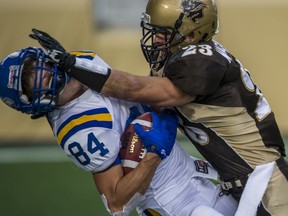UBC Thunderbirds’ receiver David Scott (left) takes it on the chin from Manitoba Bisons’ defensive back Brett Macfarlane during Canada West football game won 28-24 by UBC on Saturday in Winnipeg. (Photo – David Lipnowski, Bisons Athletics)