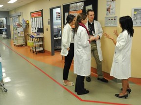 Dermatologist Dr. Sheila Au (right) speaks to physician trainees Amanda Israel, a third-year medical student, and residents Drs. Kristin Noiles and Mark Kirchhof in the acute-care area of the emergency department of St. Paul’s Hospital. Canada could face a glut of doctors, authors warn. (Jason Payne/PNG FILES)