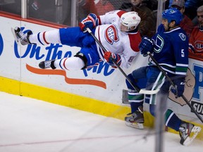 The Canucks' Jason Garrison checks the Canadiens' Lars Eller on Oct. 13, 2013. CP photo.