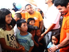 Boxing hero Manny Pacquiao (R) visits an evacuation center in Tacloban City on December 2, 2013, among the  hardist hit by Super typhoon Haiyen in Central Philippines last November 8. Philippine boxing hero Pacquiao handed out Bibles, tinned food and cash to lift people's spirits in areas devastated by the typhoon.   AFP PHOTO  DENNIS JAY SANTOS/AFP/Getty Images
