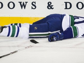 Andrew Alberts of the Vancouver Canucks lies motionless after being knocked out by the Calgary Flames' Brian McGrattan on Dec. 29, 2013 in Calgary. CP photo.