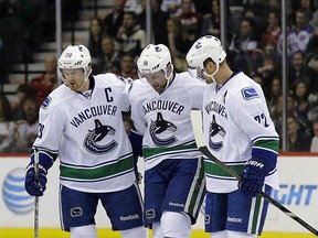 Henrik (left) and Daniel Sedin help injured defenceman Ryan Stanton off the ice after he was injured Tuesday in St. Paul, Minn.