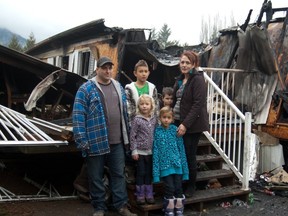 The Perry/Robberstad family, including  nine-year-old Shamus, seven-year-old twins Constance and Veronica and four-year-old Billy, stand in front of their burned home.