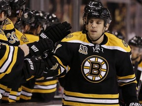 Boston Bruins' Milan Lucic is congratulated at the bench by teamates after a goal against the New Jersey Devils during the first period of an NHL hockey game in Boston, Saturday, Oct. 26, 2013. Lucic says he's "done trying to defend" his hometown of Vancouver after he claims he was punched twice at a nightclub." THE CANADIAN PRESS/AP/Winslow Townson